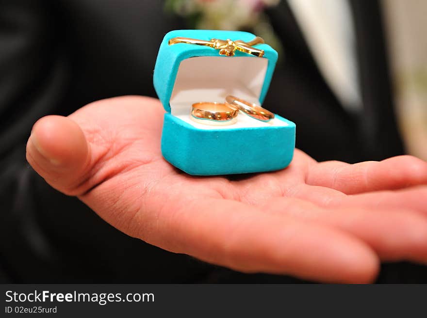 Bridegroom holding wedding rings on the palm. Shallow DOF