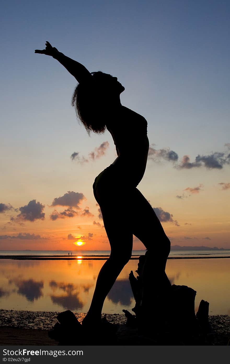 A silhouette of a woman facing the sunset in a yoga pose. A silhouette of a woman facing the sunset in a yoga pose