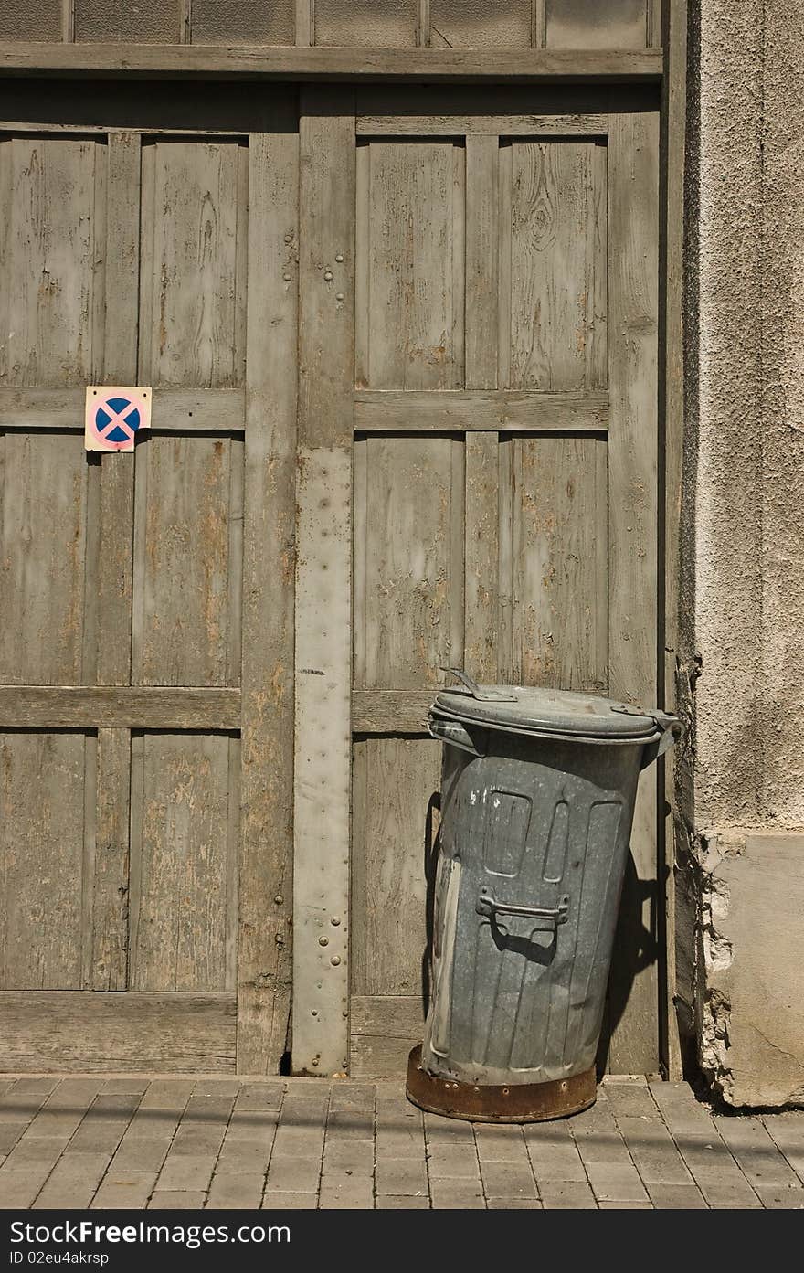 Rusty trash can in front of old wooden door. Rusty trash can in front of old wooden door