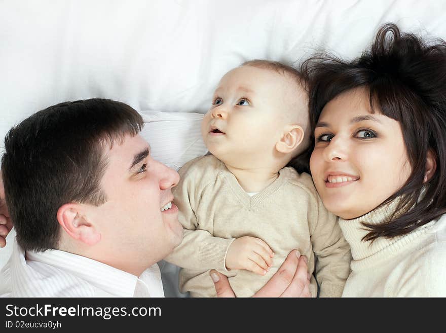 Happy family home: father, mother and baby lying on the floor and playing. Happy family home: father, mother and baby lying on the floor and playing