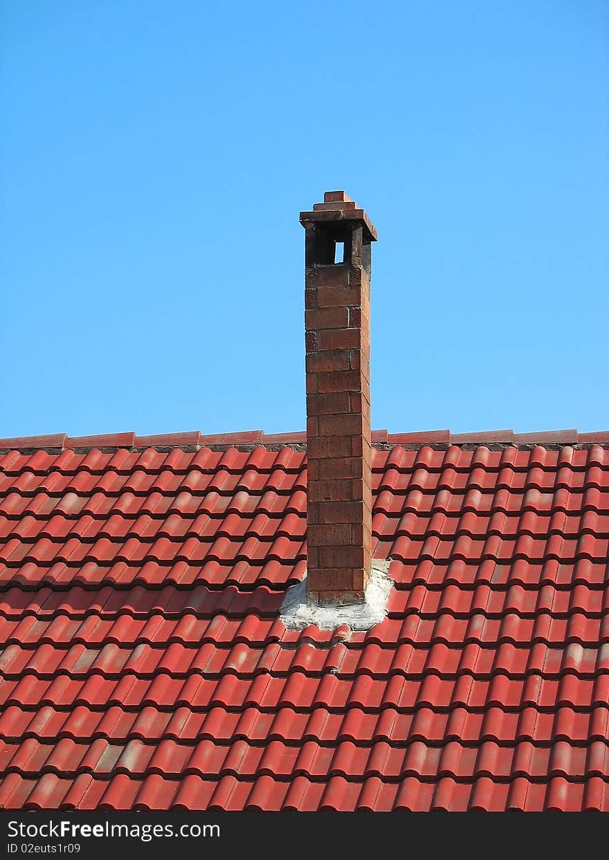 Red Brick Chimney On Tile Roof Over Blue Sky