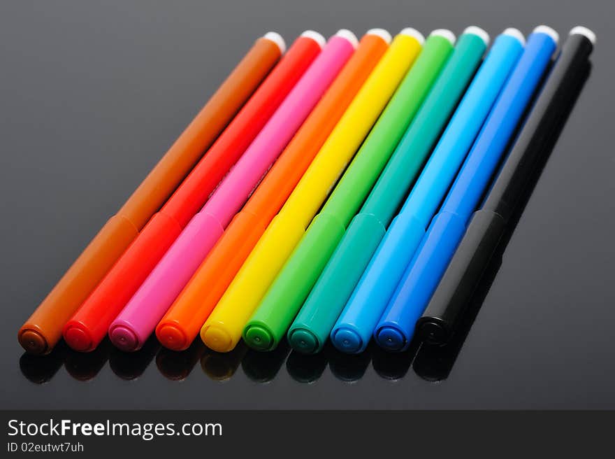 A set of colored felt pens on a black background