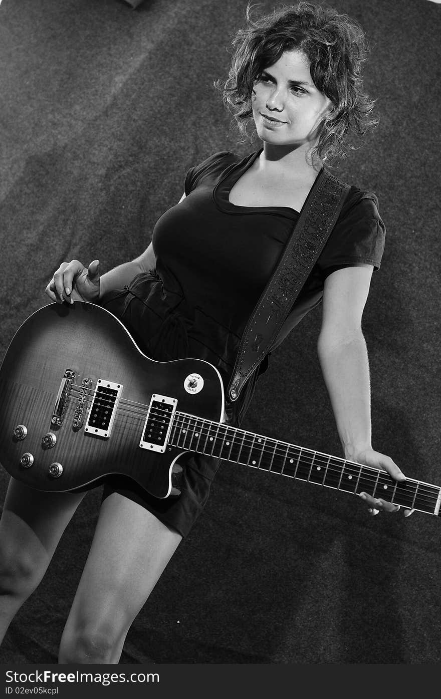 Portrait of young woman holding electric guitar in black and white. Portrait of young woman holding electric guitar in black and white