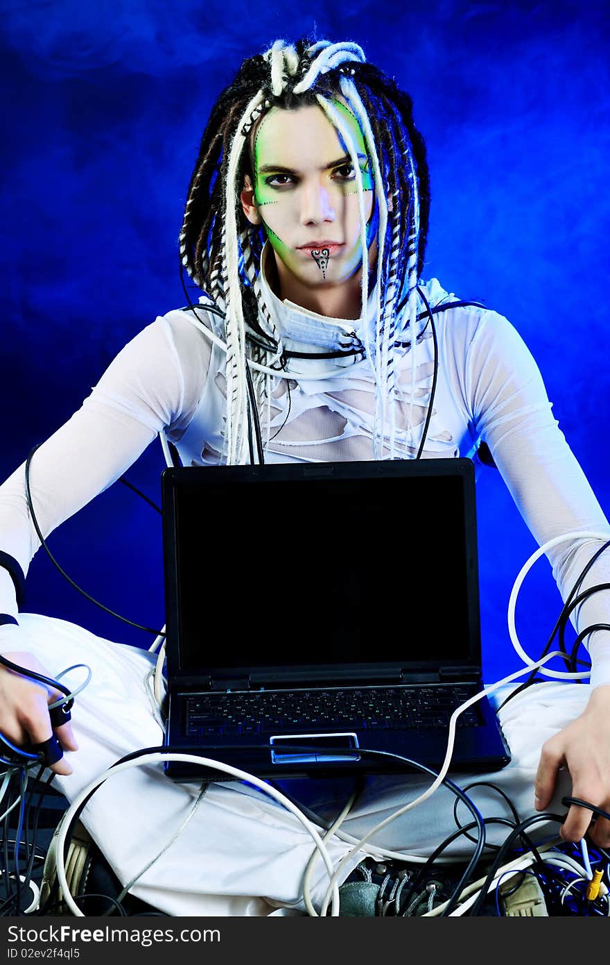 Shot of a futuristic young man sitting with a laptop and wires. Shot of a futuristic young man sitting with a laptop and wires.