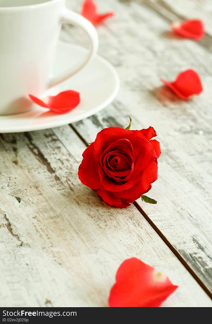 red rose and cup on old wooden