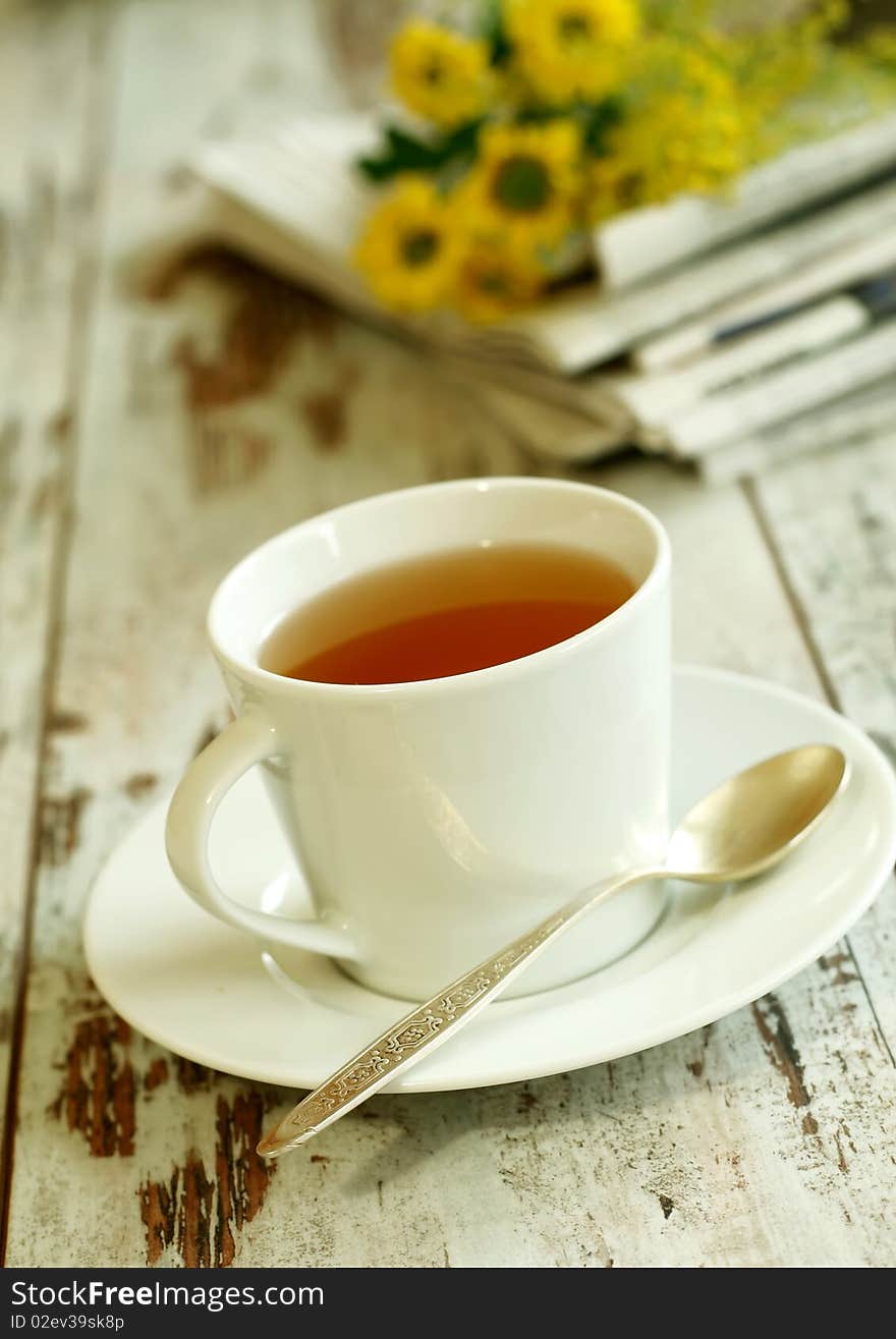 cup of tea, newspaper and flowers on old wooden