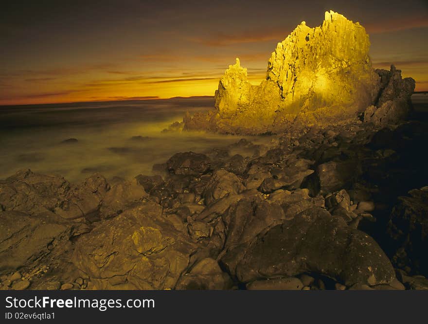 Rocky coast at sunset with rocks in foreground. Rocky coast at sunset with rocks in foreground