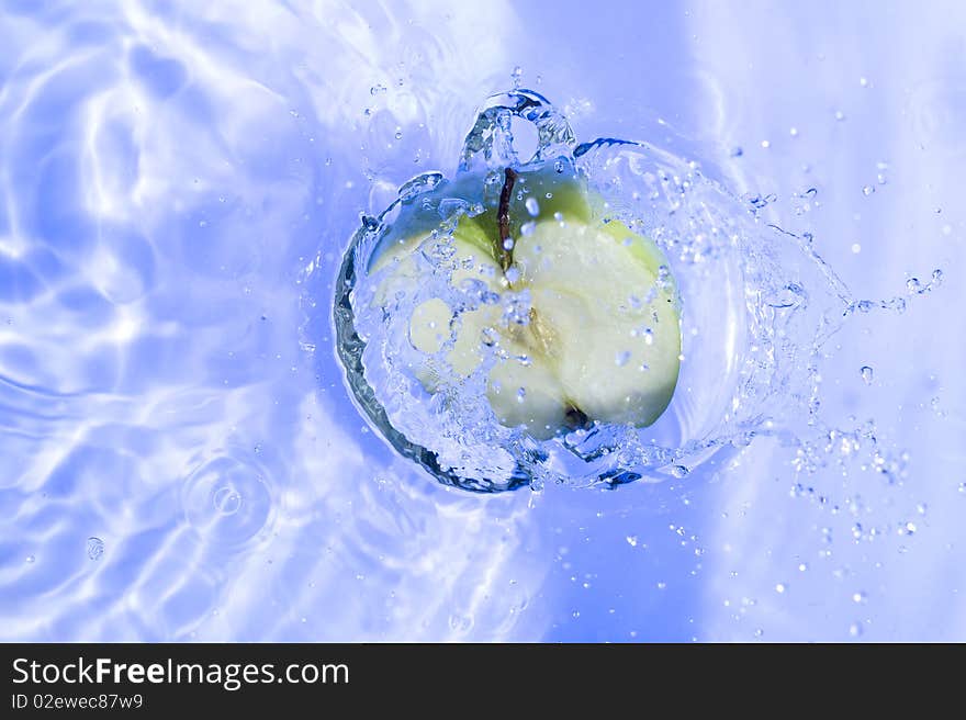 Apple with splashing  blue water. Freshness fruit