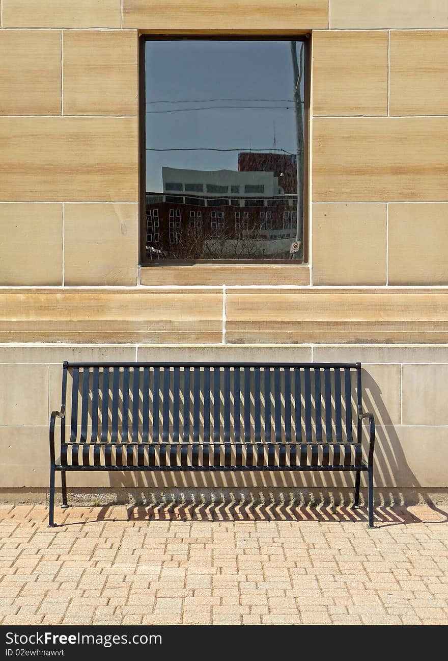 Image of a solitary bench under a window with vintage building background and interlocking ground surface. Image of a solitary bench under a window with vintage building background and interlocking ground surface.