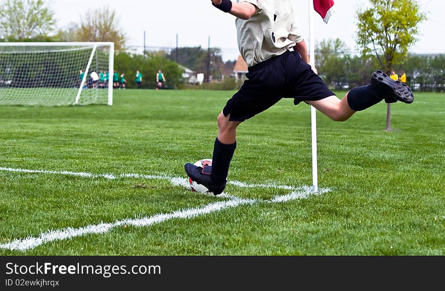 A boy kicks a soccer ball from a goal corner during a youth soccer game. A boy kicks a soccer ball from a goal corner during a youth soccer game.