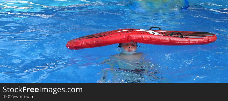 Boy in pool with an inflatable bed on his head