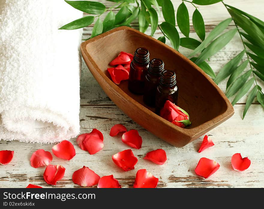 Spa composition of towel, bottles and red petals