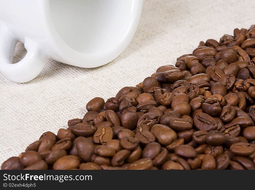 White cup, beans at textile material