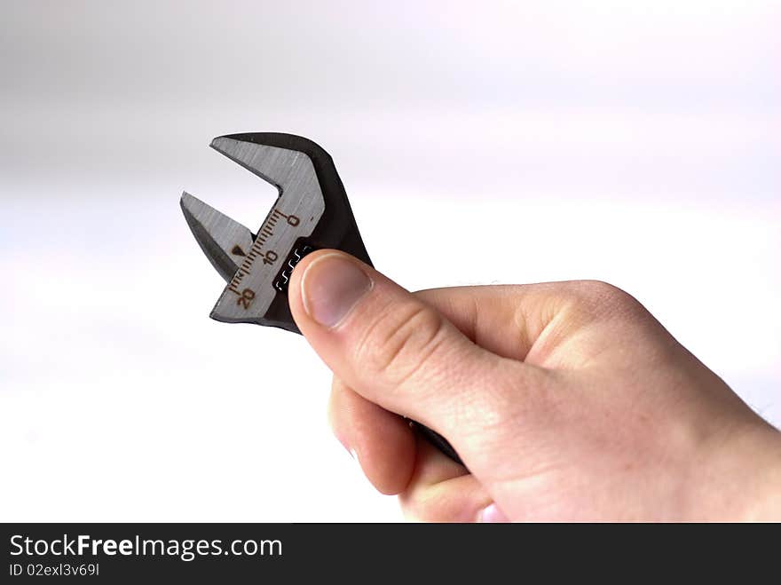 A hand holdning an adjustable spanner isolated on a white background