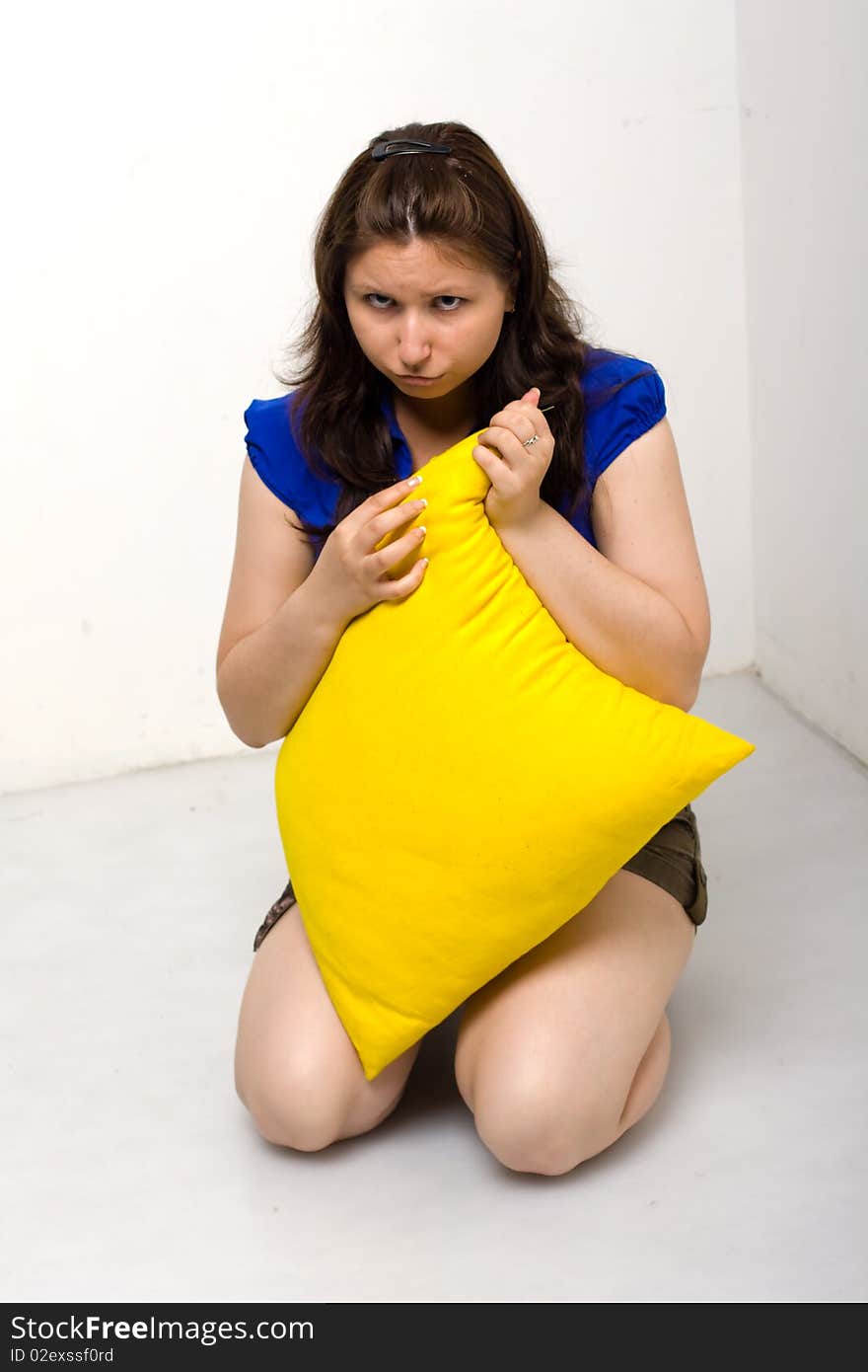 Pretty young girl with black hair isolated on white background, holding a yellow pillow. Pretty young girl with black hair isolated on white background, holding a yellow pillow