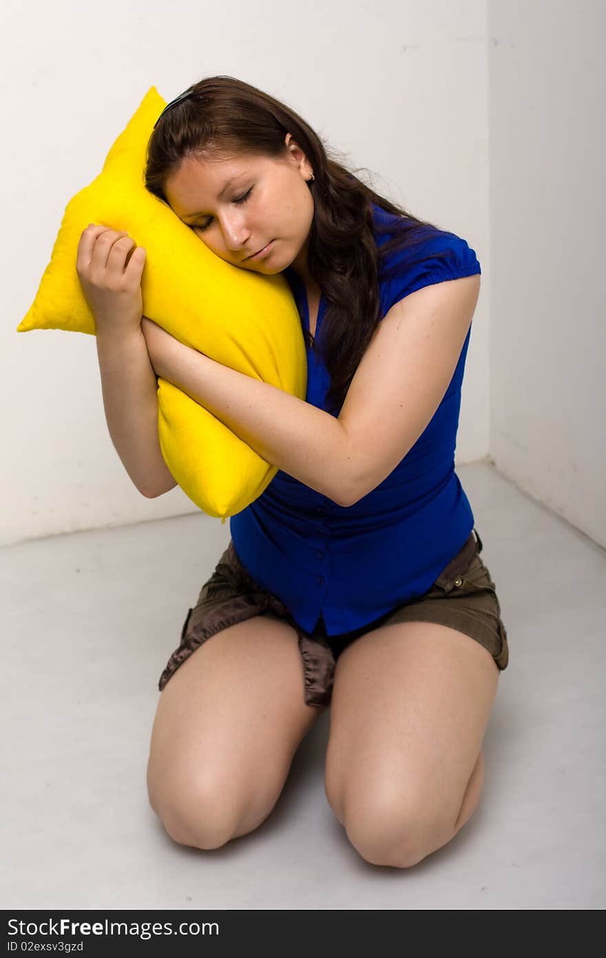 Pretty young girl with black hair isolated on white background, holding a yellow pillow. Pretty young girl with black hair isolated on white background, holding a yellow pillow