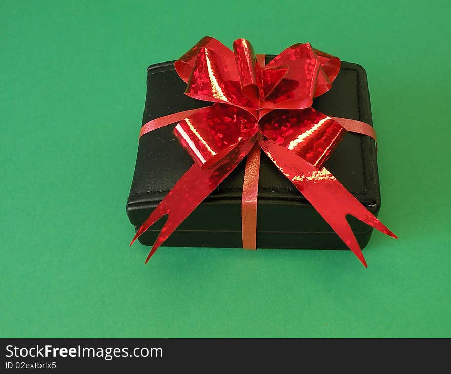 Black gift box with red ribbon isolated on green