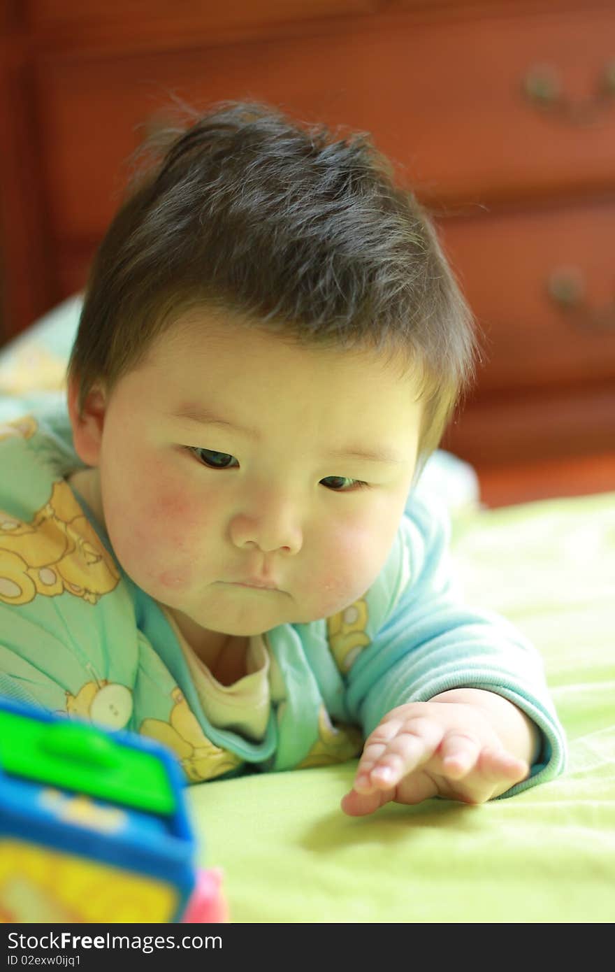 Lovely Chinese baby playing in the bed with some toys. Lovely Chinese baby playing in the bed with some toys