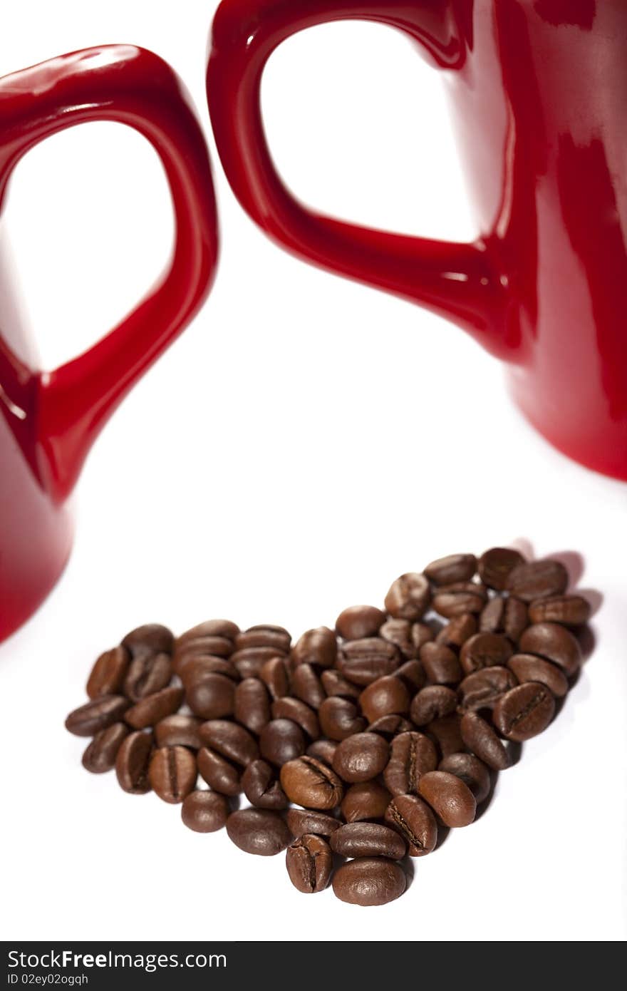 Coffee-beans heart against red cup`s handles on white backround