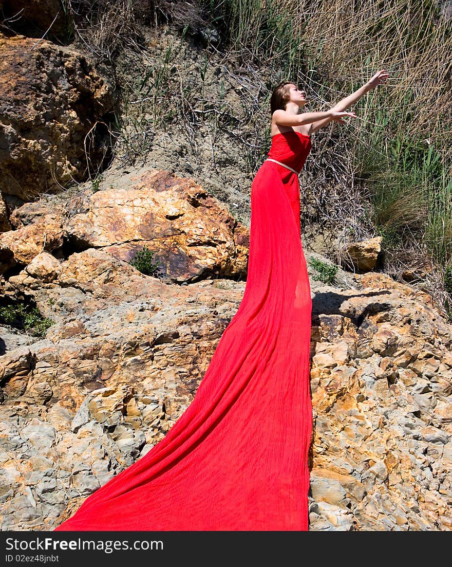 Woman in red dress from material and rocks