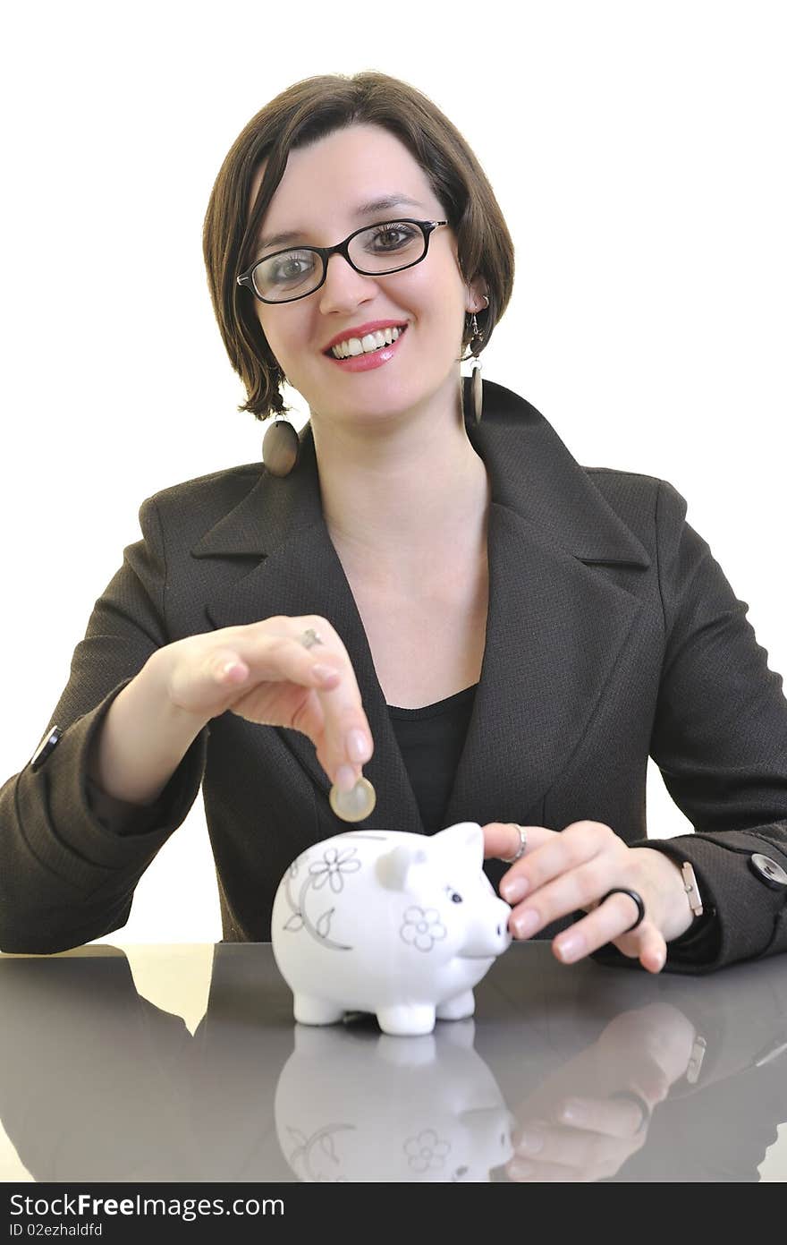 Young business woman iosolated on white putting coins money in piggy bank and representing concept of saving and smart spending money. Young business woman iosolated on white putting coins money in piggy bank and representing concept of saving and smart spending money