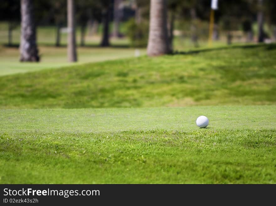 Golf ball on tee in a beautiful green grass golf course,photographed with shallow DOF (Lifestyle concept)