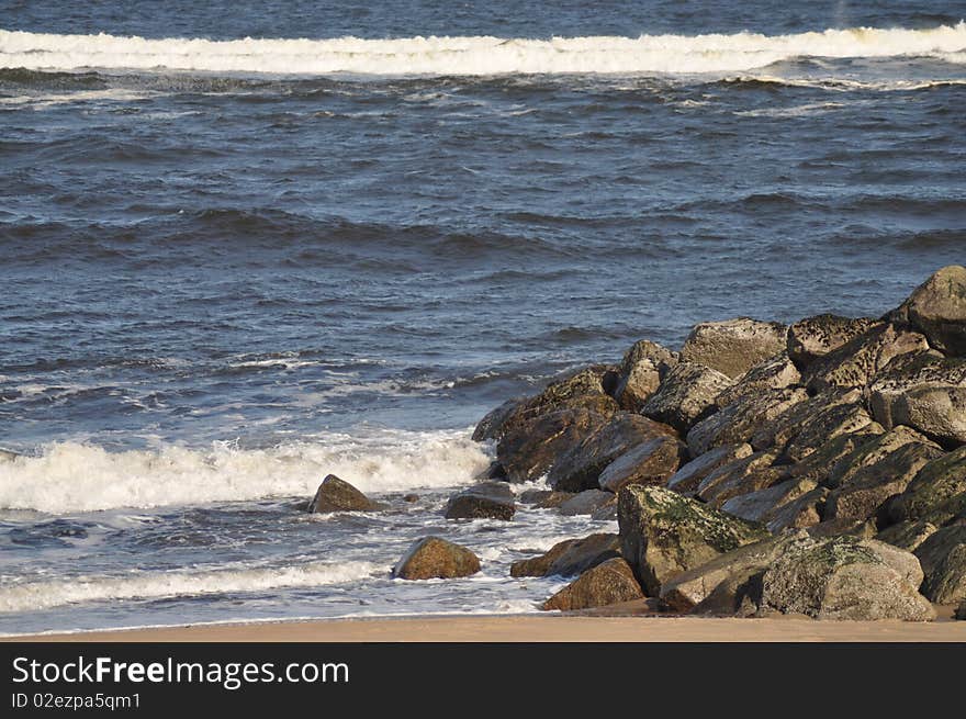 Waves break on a rock jetty in New England on the shore. Waves break on a rock jetty in New England on the shore.