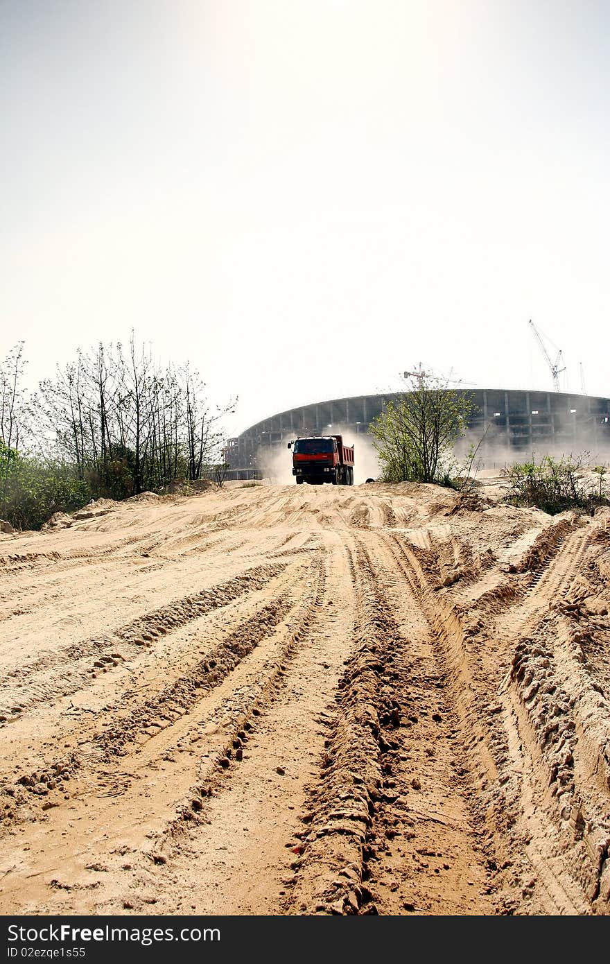 A view of a yellow construction water tanker truck spraying water for dust control at construction site. A view of a yellow construction water tanker truck spraying water for dust control at construction site.