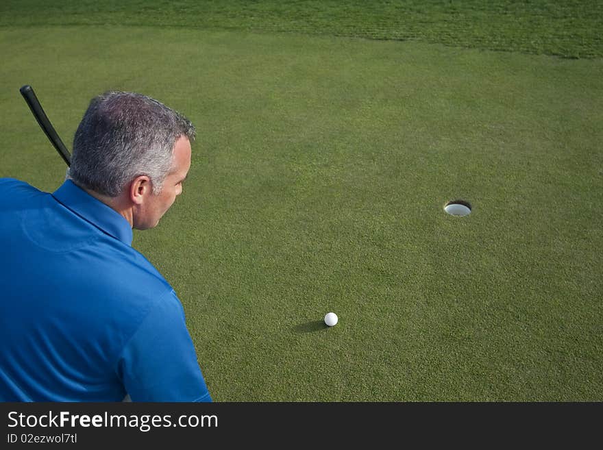 A handsome mature male golfer in his 50s on the putting green ready to make a putt. Lots of Copy Space. A handsome mature male golfer in his 50s on the putting green ready to make a putt. Lots of Copy Space