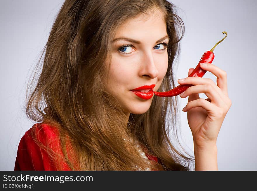 Portrait of a young beautiful girl holding her mouth red chili peppers. Portrait of a young beautiful girl holding her mouth red chili peppers