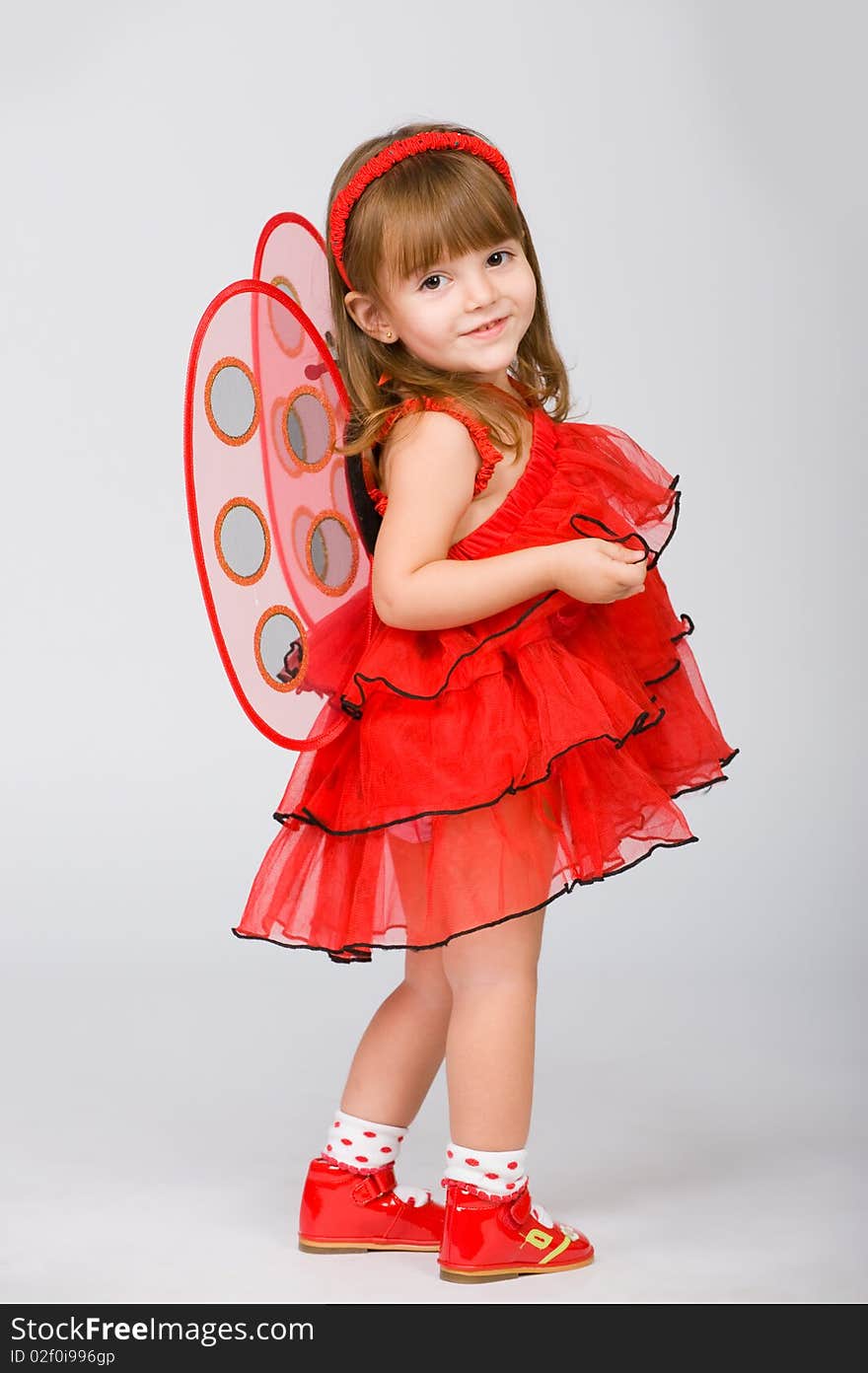 Little girl in a red dress and wings behind. Little girl in a red dress and wings behind