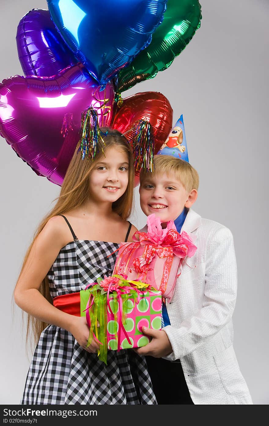 Beautiful boy and girl standing side by side with gifts and balloons in their hands. Beautiful boy and girl standing side by side with gifts and balloons in their hands