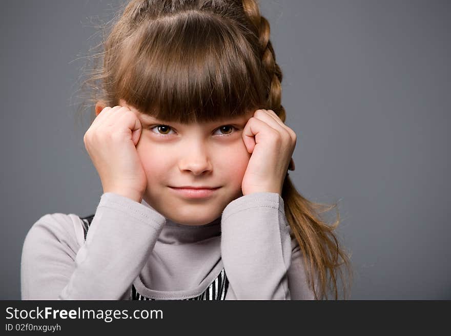 Portrait of a beautiful little girl in a gray sweater, sitting on a chair. Portrait of a beautiful little girl in a gray sweater, sitting on a chair