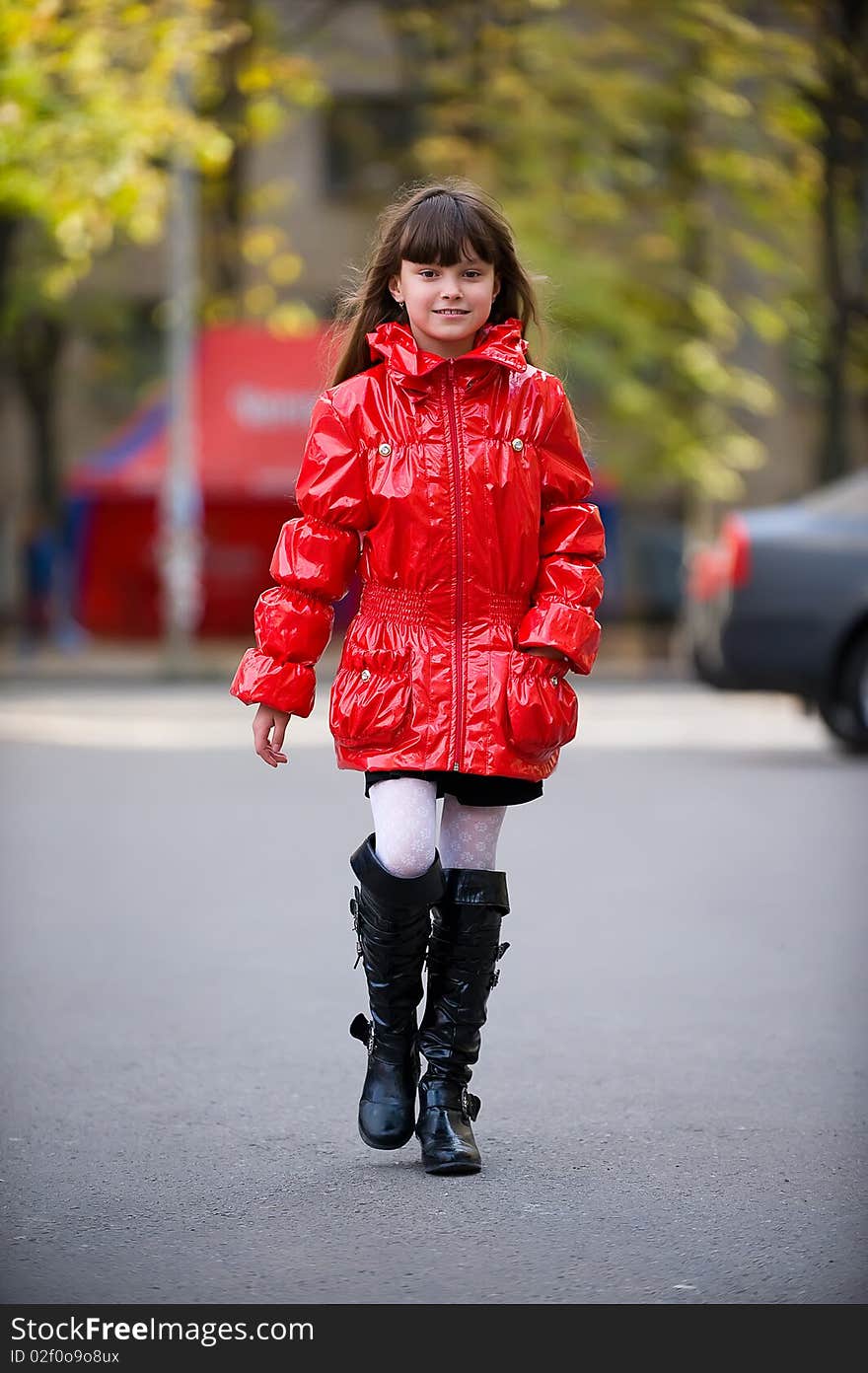 Young girl in a red jacket walking along the street. Young girl in a red jacket walking along the street