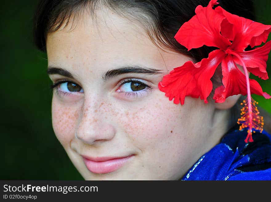 A tween girl with a red hibiscus in her hair. A tween girl with a red hibiscus in her hair.