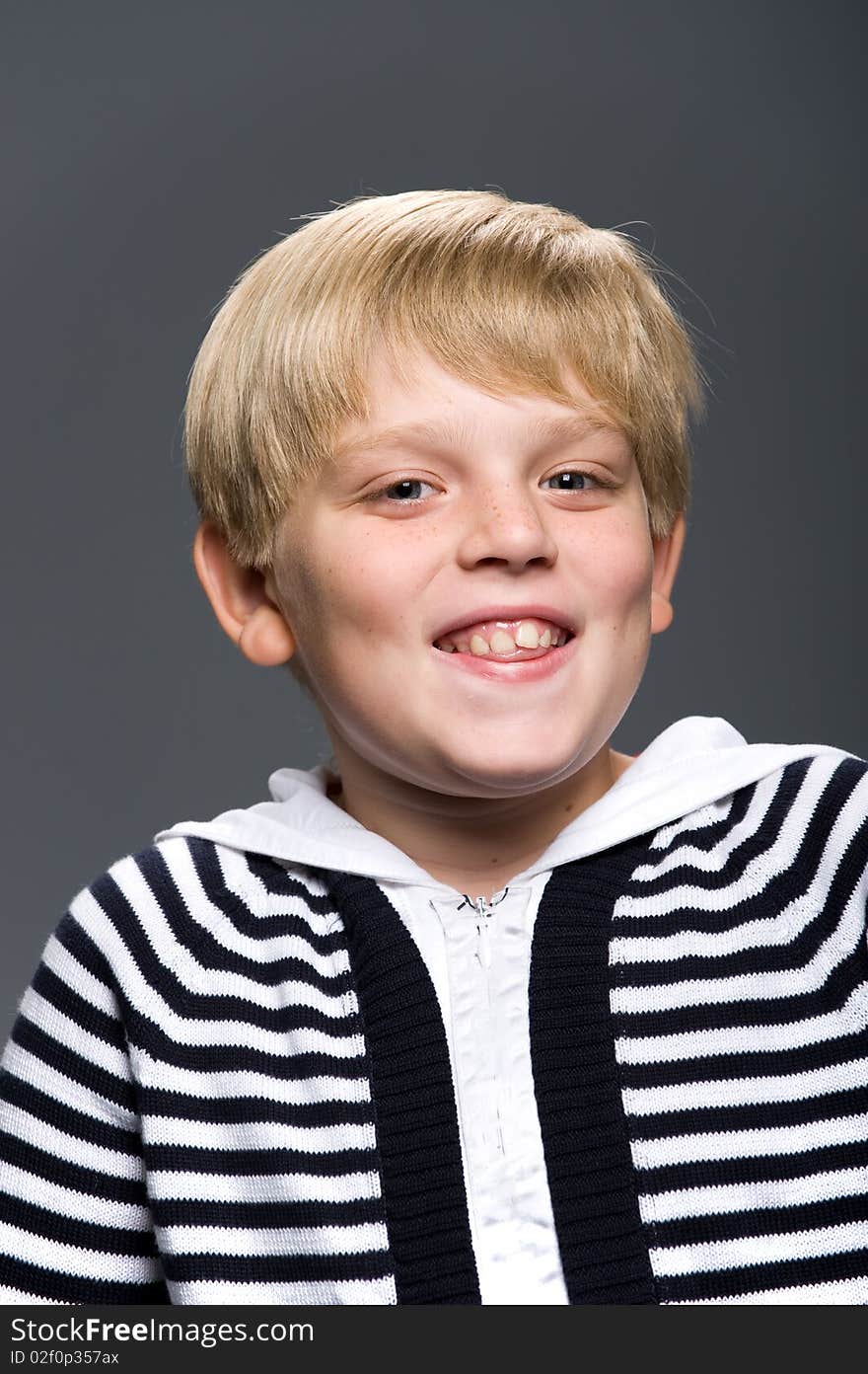 Portrait of young blond man in a striped sweater with a gray background. Portrait of young blond man in a striped sweater with a gray background