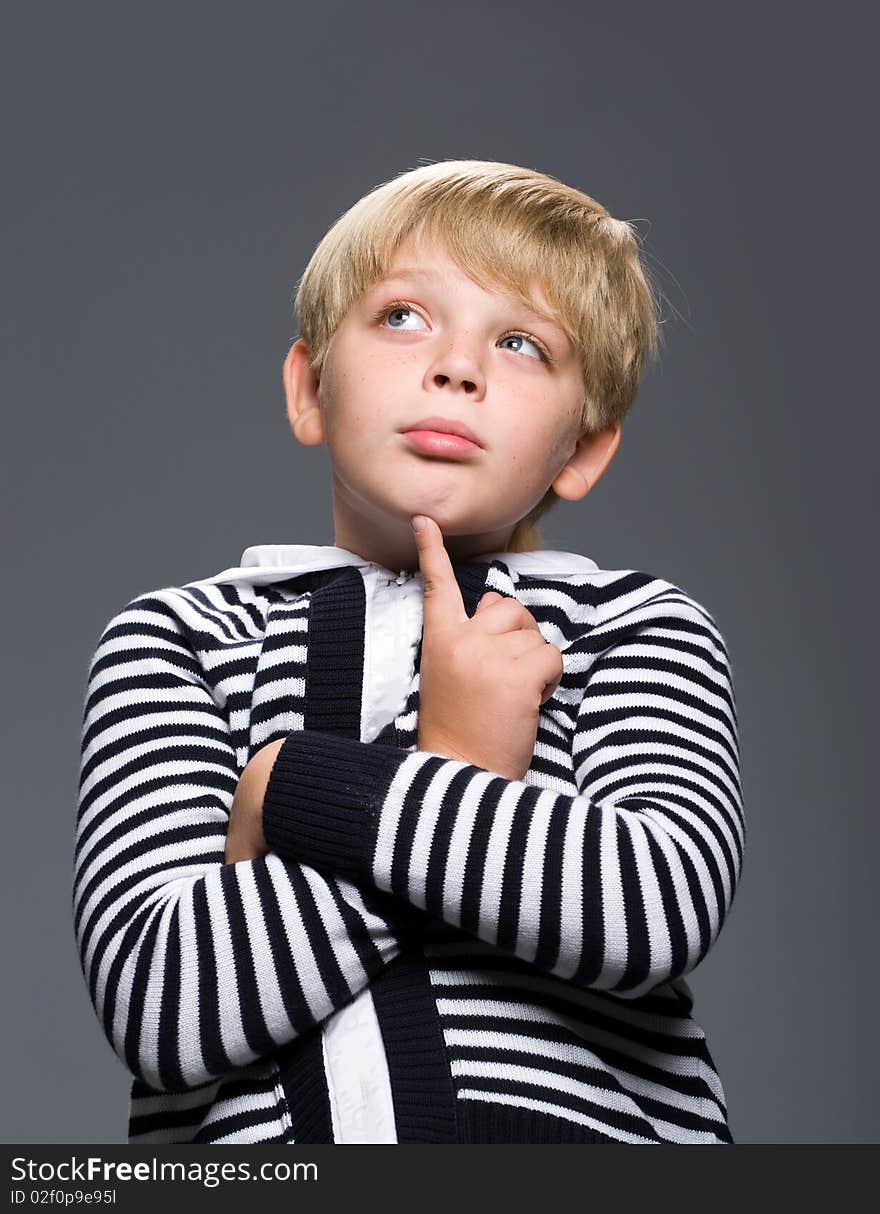 Portrait of a pensive boy in a striped sweater with a gray background. Portrait of a pensive boy in a striped sweater with a gray background