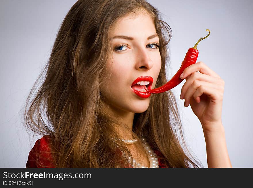 Portrait of a young beautiful girl holding her mouth red chili peppers. Portrait of a young beautiful girl holding her mouth red chili peppers