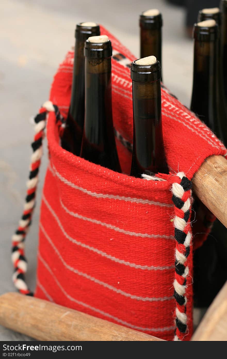 Wine bottles in traditional woven handbag, with red and white traditional folk design