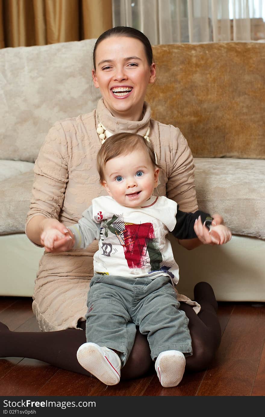 Happy young beautiful mother with her little son in home interior