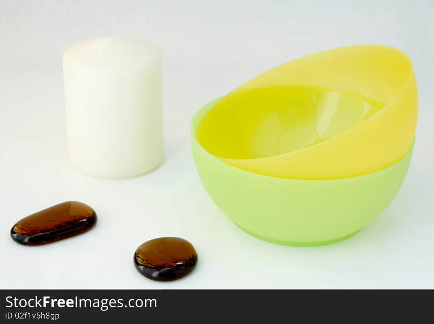 Candle, decorative stones, bowl on the white background