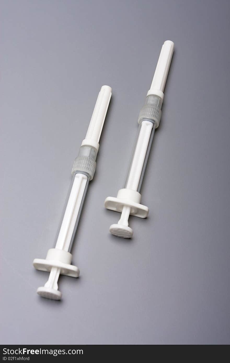 Two syringes on a grey background