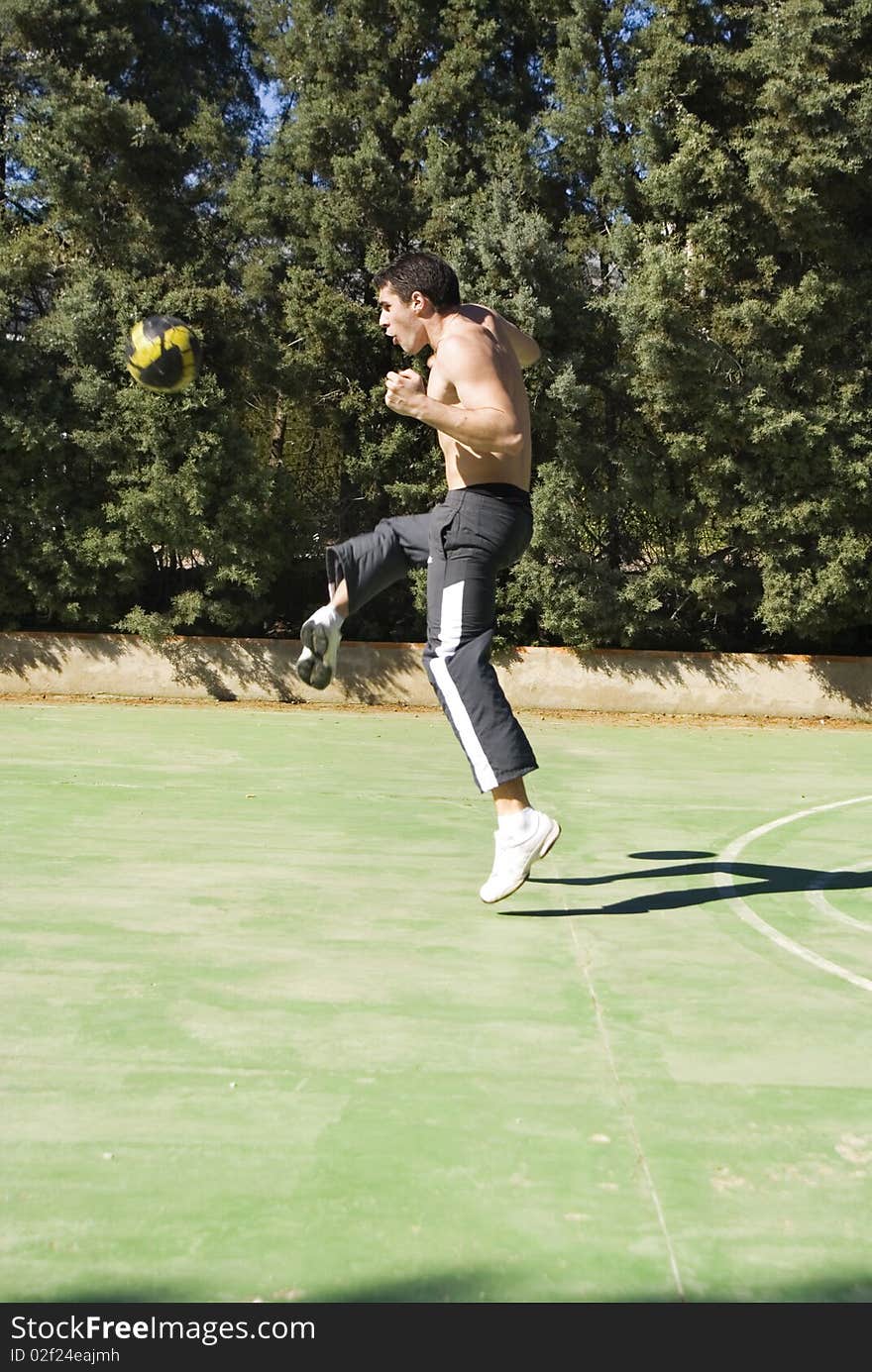 Young man playing football kicking the ball