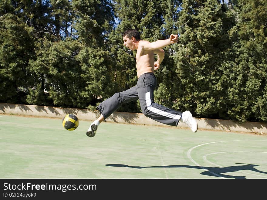 A young man playing football kicking the ball. A young man playing football kicking the ball