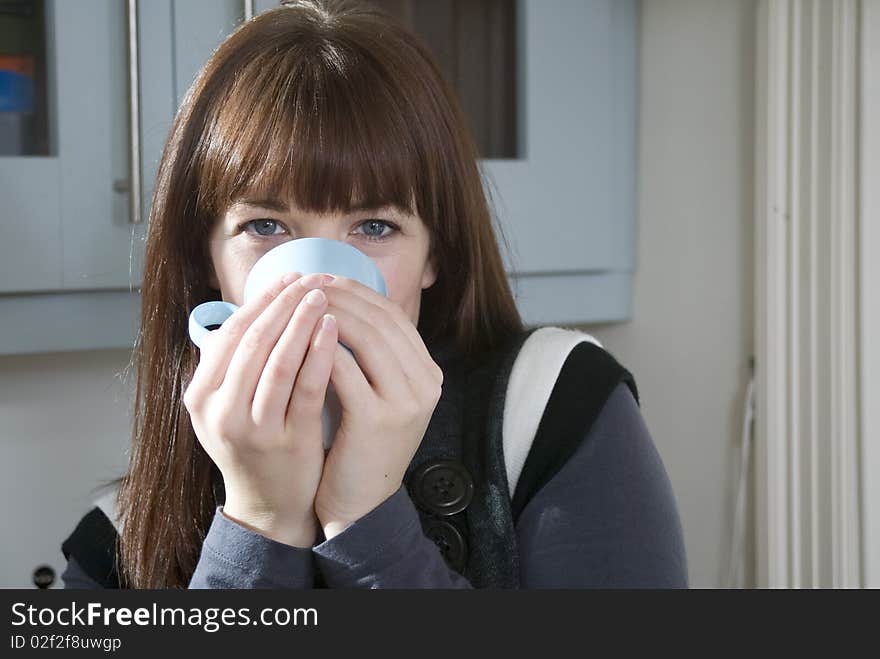 A woman drinking a hot drink at home.