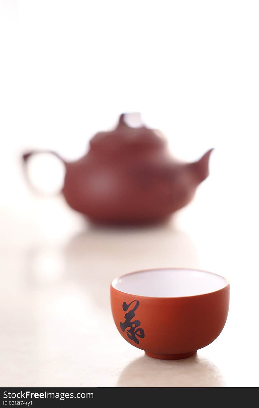 Chinese teacup and pot on marble table. The chinese character 'Tea' is on the teacup.