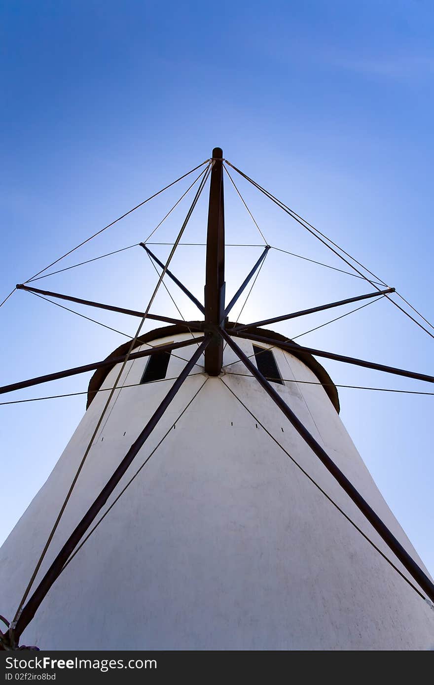 A close up look at a windmill. Looking directly up at it with blue skies behind it. A close up look at a windmill. Looking directly up at it with blue skies behind it.