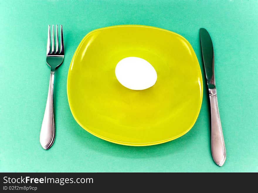 Plate, knife and fork against green background. Plate, knife and fork against green background