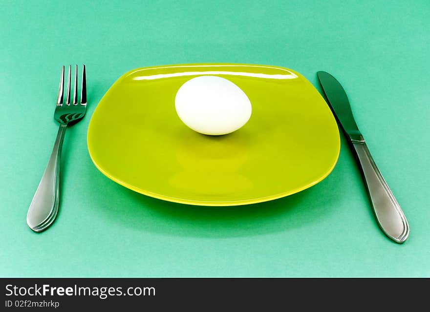 Plate, knife and fork against green background. Plate, knife and fork against green background