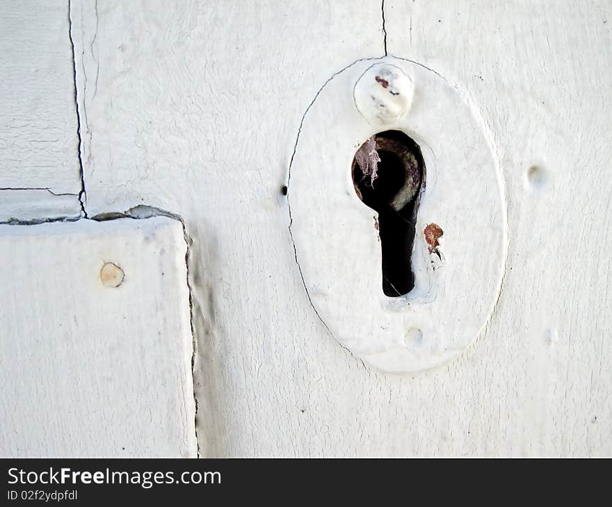 Detail of old white wooden door with keyhole.